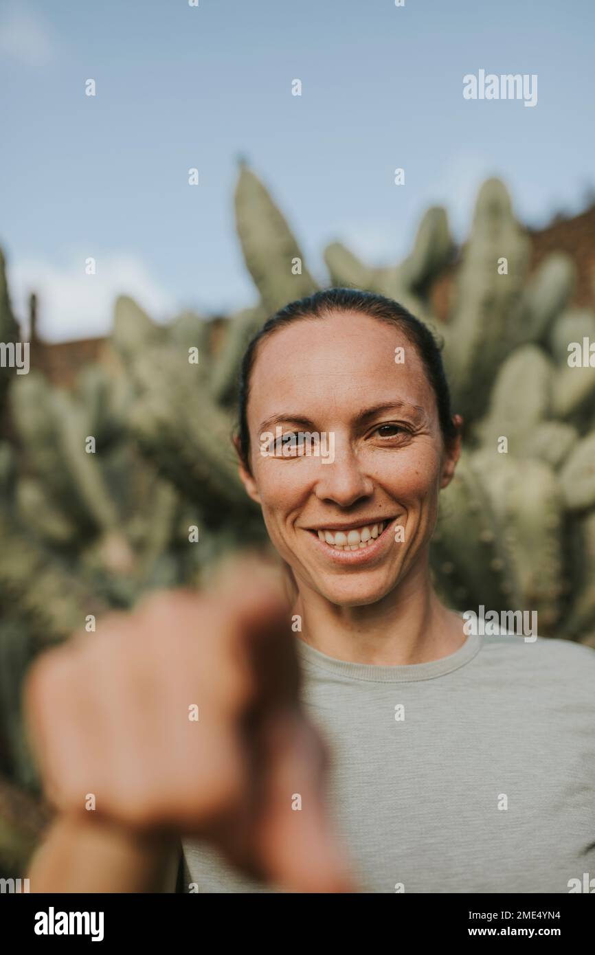 Glückliche Frau, die im Kaktusgarten Gesten macht Stockfoto