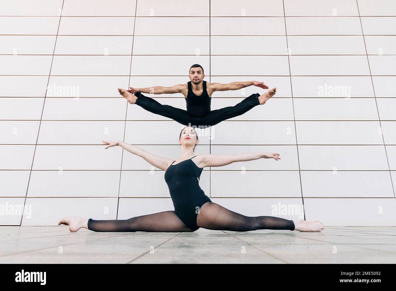 Ein Paar tanzt mit gespreizten Beinen vor der Wand Stockfoto