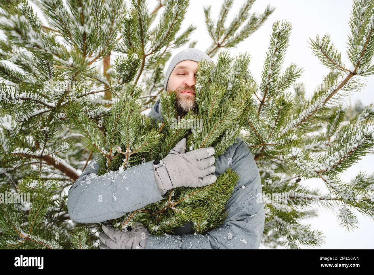 Ein Mann, der im Winterurlaub Kiefern umarmt Stockfoto