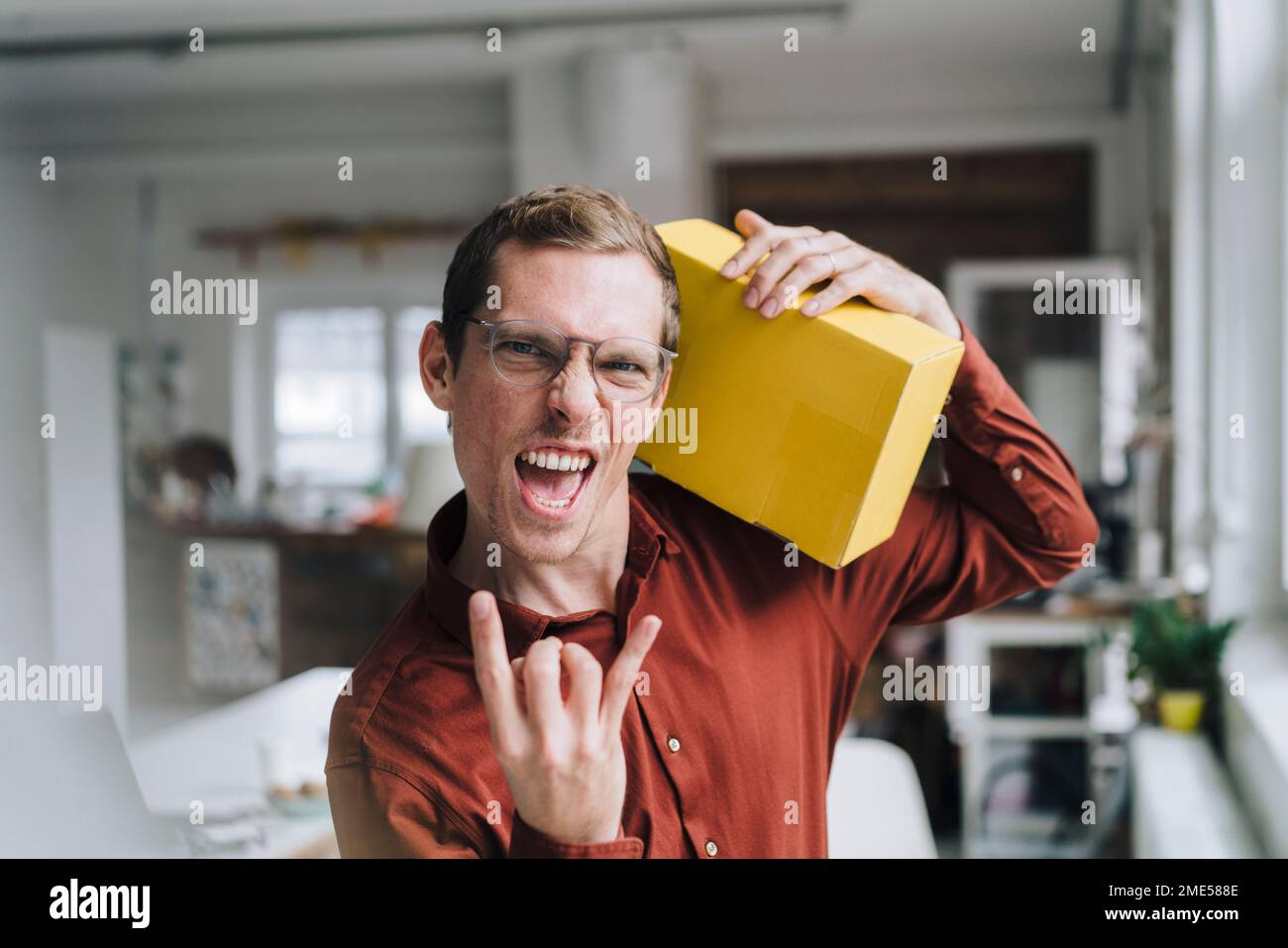 Fröhlicher Geschäftsmann, der im Büro mit einer Box steht Stockfoto
