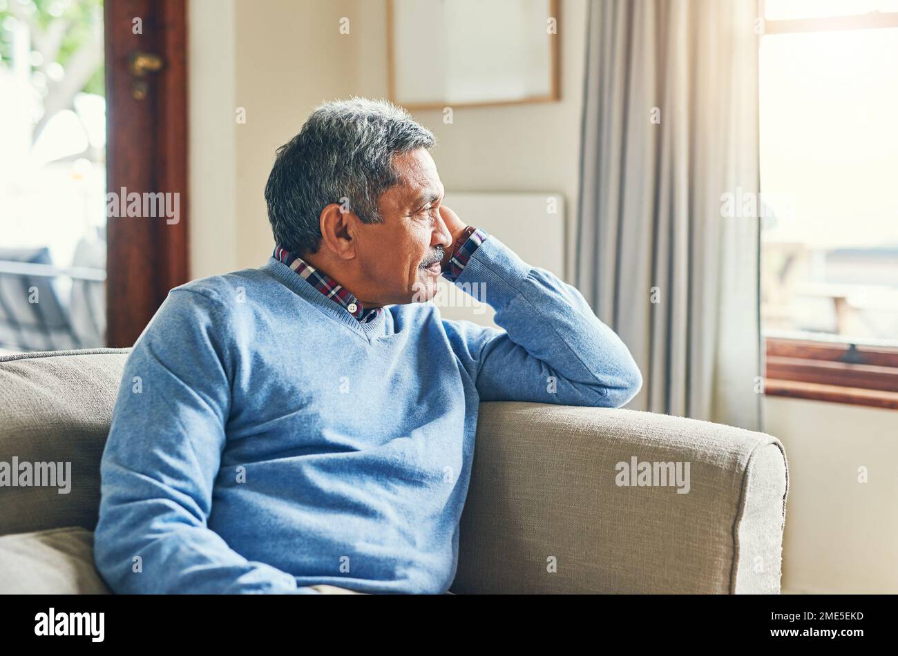 Wer hätte gedacht, dass ich es so weit schaffe? Ein älterer Mann, der sehr aufmerksam aussah, während er sich zu Hause auf dem Sofa entspannte. Stockfoto