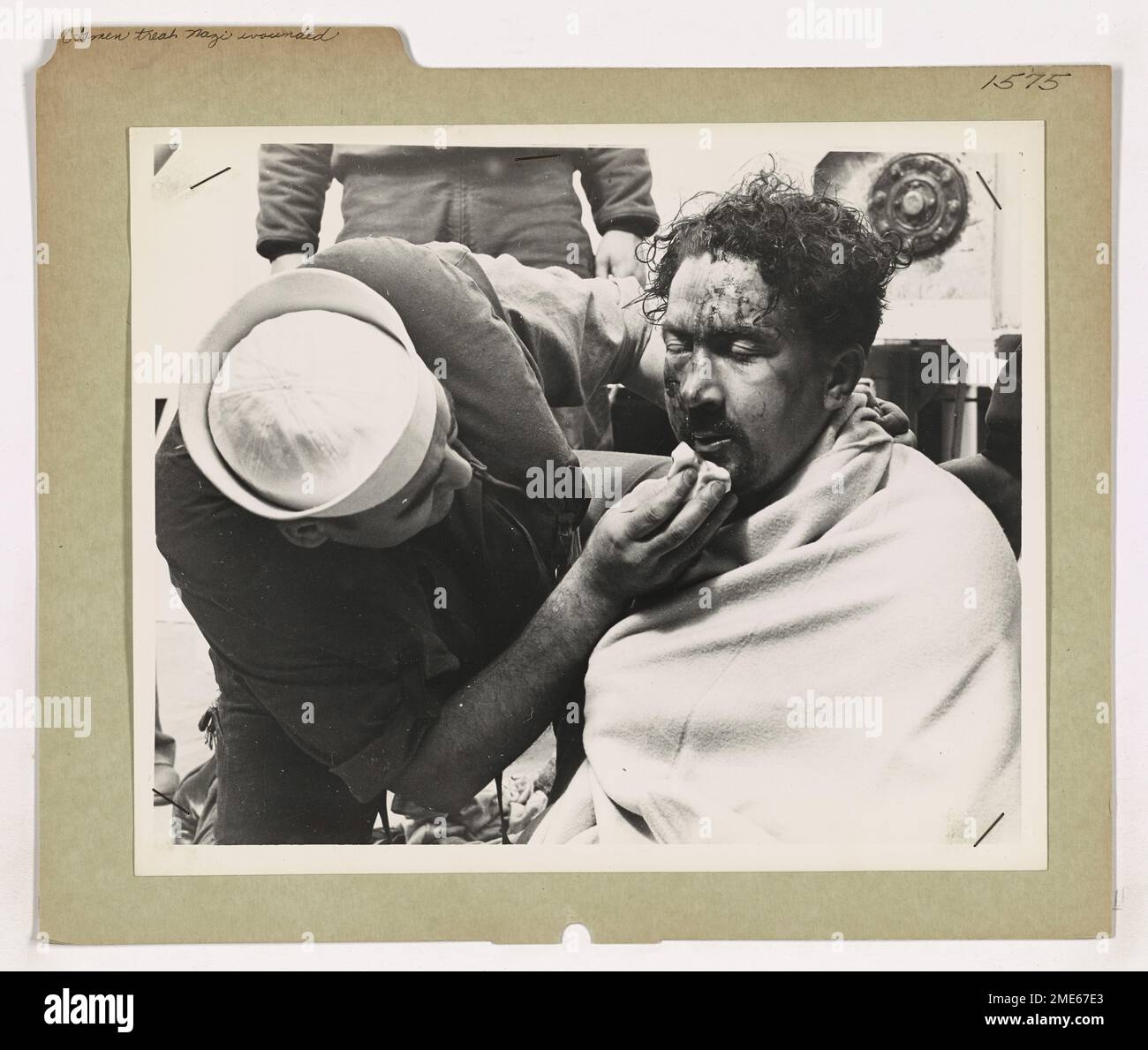 Ein Küstenwächter kümmert sich um einen gefangenen Nazi-Matrosen, der verletzt wird, als sein U-Boot von alliierten Truppen versenkt wurde. Dieses Bild zeigt die Professionalität des US-Militärs, das selbst im Kampf die Kriegsregeln befolgt und Kriegsgefangene nach internationalem Recht behandelt. Stockfoto