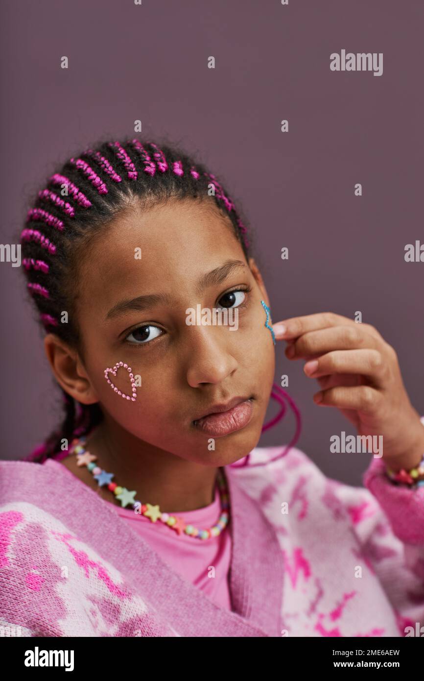 Vertikale Nahaufnahme eines schwarzen Mädchens mit glitzernden Tattoos im Gesicht, das in die Kamera schaut Stockfoto