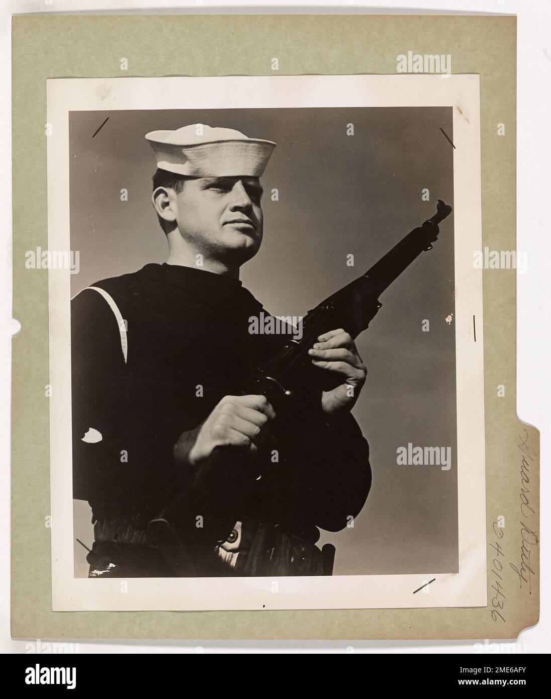 Ein US-Küstenwächter steht wachsam und hat Waffen, während er in einem amerikanischen Hafen Wachdienst hält. Küstenwache patrouillieren Tag und Nacht in den Häfen der USA und schützen Docks, Kais und Schifffahrt vor potenziellen Bedrohungen wie Sabotage. Stockfoto