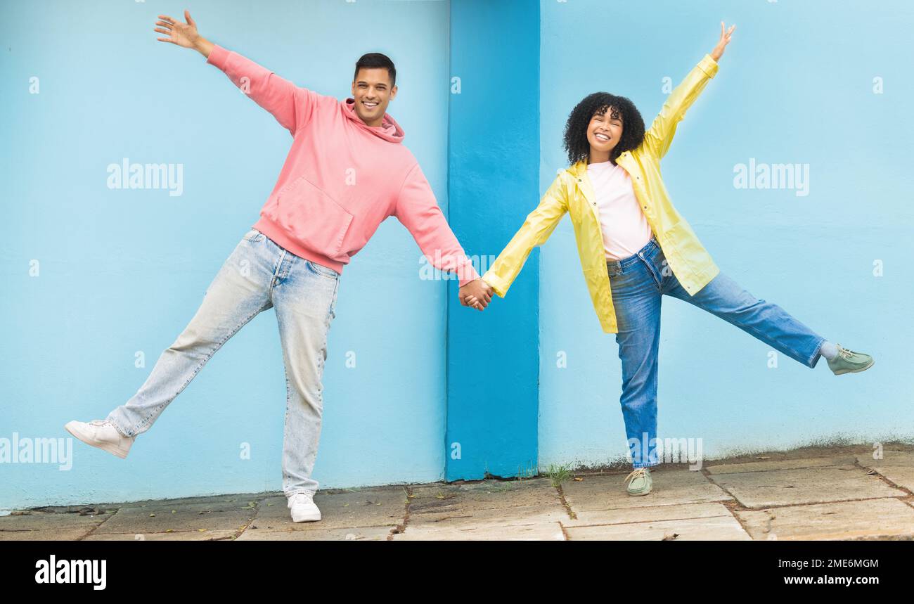 Fröhliches, lächelndes und glückliches Paar, das Händchen in der Straße hält und eine alberne, lustige und alberne Pose macht. Glück, Liebe und junge Männer und Frauen Stockfoto
