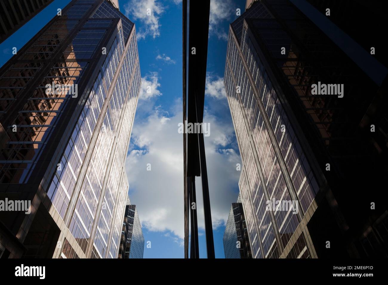 Spiegelbild von Gebäuden mit blauem Himmel und Wolken, die in großen Glasscheiben reflektiert werden, Montreal, Quebec, Kanada. Stockfoto