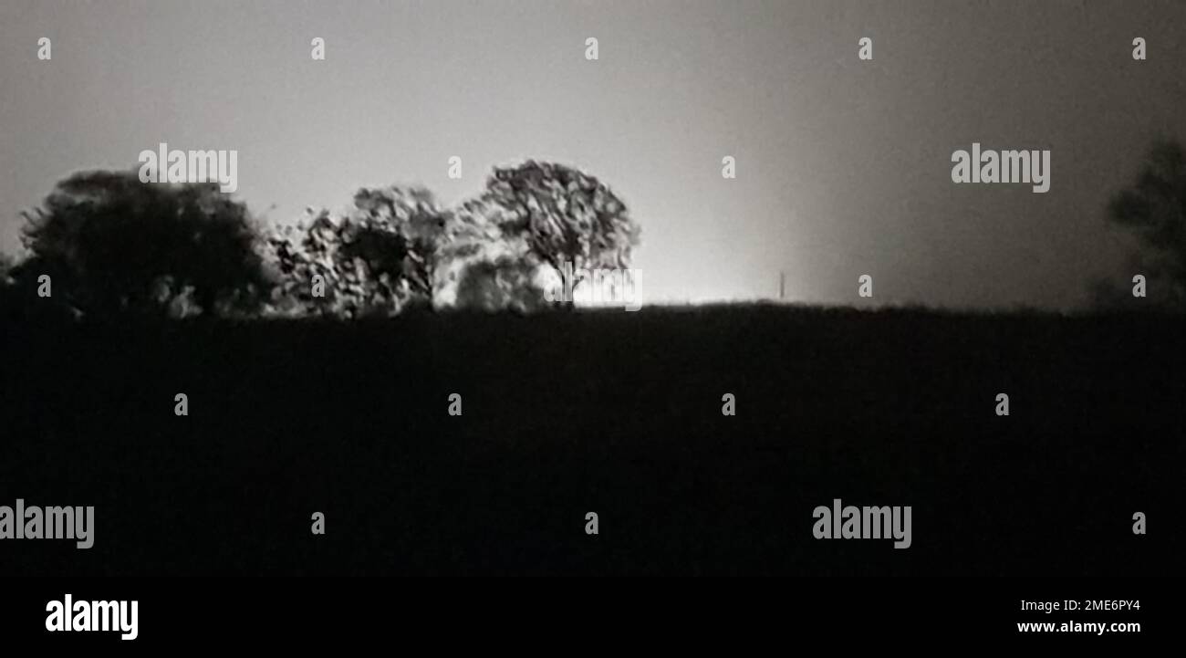 Ein Panoramablick auf eine Landschaft und die Schatten einiger Bäume bei Nacht Stockfoto