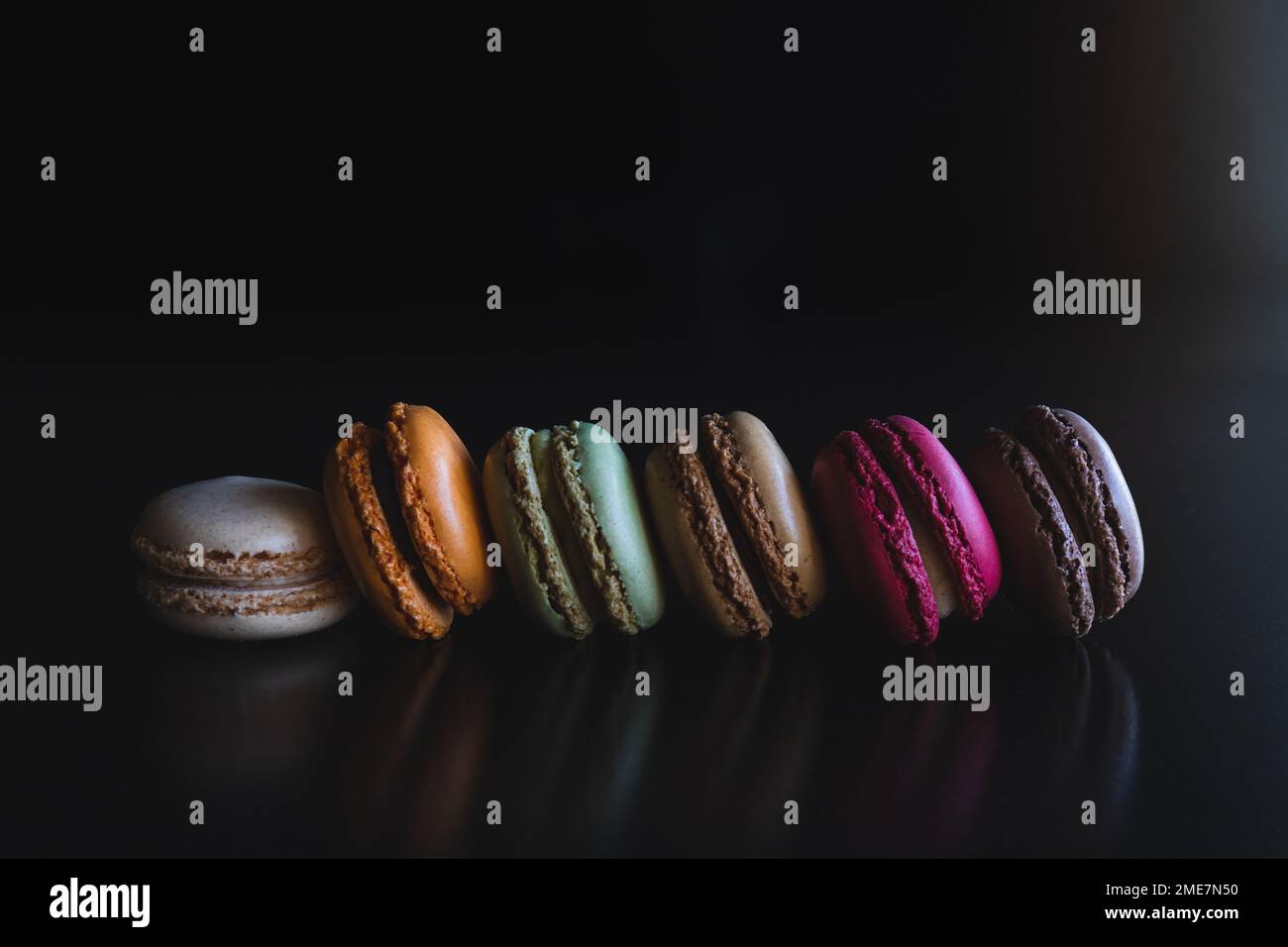 Eine Reihe farbenfroher Makaron-Cookies auf schwarzem Hintergrund Stockfoto
