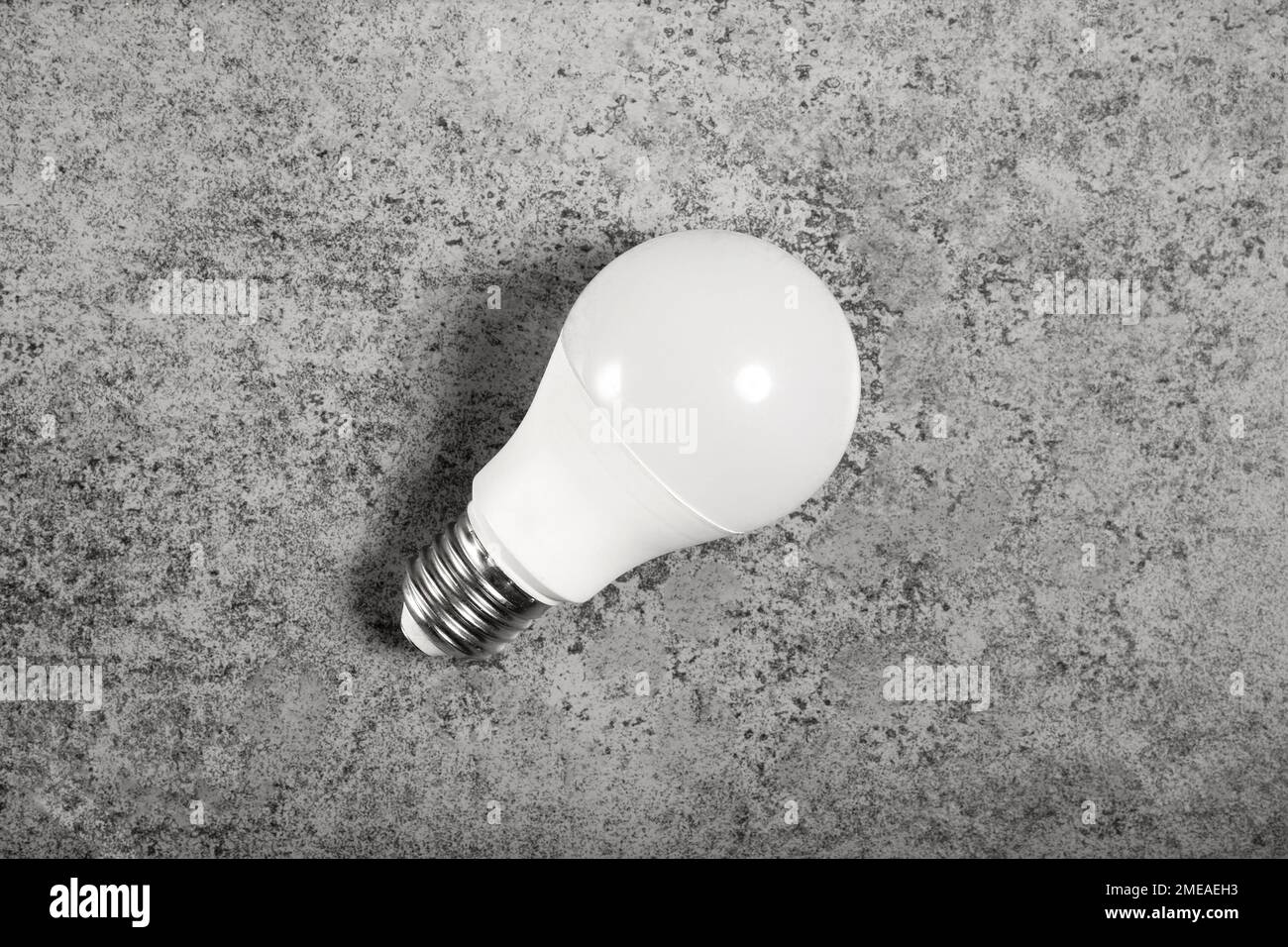 Einfache Standard-LED-Energiesparlampe mit E27-Sockel mit Schraubverschluss auf grauem Hintergrund Stockfoto