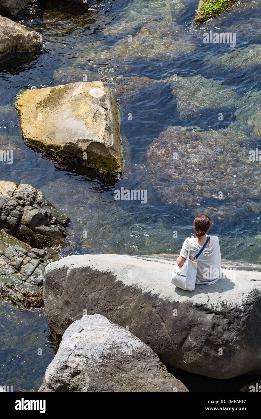 Solofrau sitzt auf Felsen im Ligurischen Meer, in Riomaggiore, Cinque Terre, Italien. Stockfoto