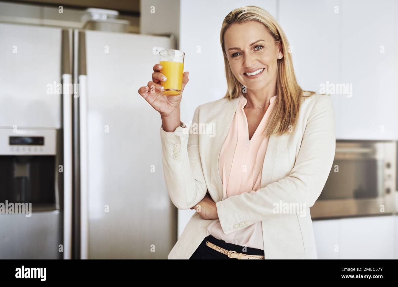 Man muss die Vitaminwerte hoch halten. Porträt einer fröhlichen Geschäftsfrau mittleren Alters, die tagsüber ein Glas Orangensaft in der Küche genießt Stockfoto