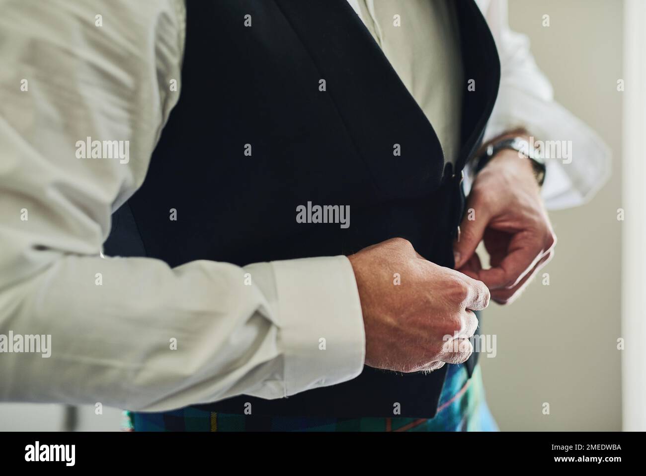 Ich muss mich beeilen, sonst komme ich zu spät. Ein unbekannter Mann, der tagsüber formelle Kleidung anzieht, um sich für eine Hochzeit in einem Gebäude vorzubereiten. Stockfoto