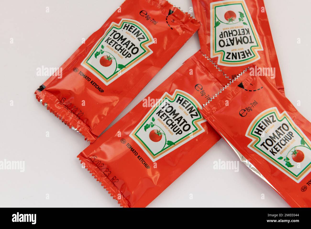 Nach London. GROSSBRITANNIEN - 01.22.2023. Kleine abgepackte Portionen Heinz-Tomatenketchup für das Catering-Geschäft, isoliert in Weiß. Stockfoto