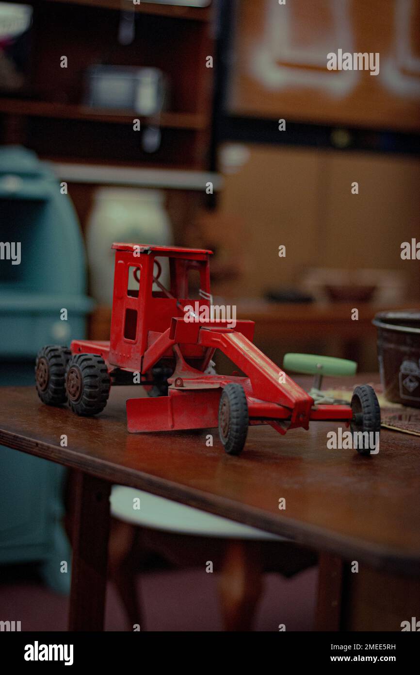 Ein vertikales Bild eines roten Miniaturtraktors in einem Second-Hand-Laden Stockfoto