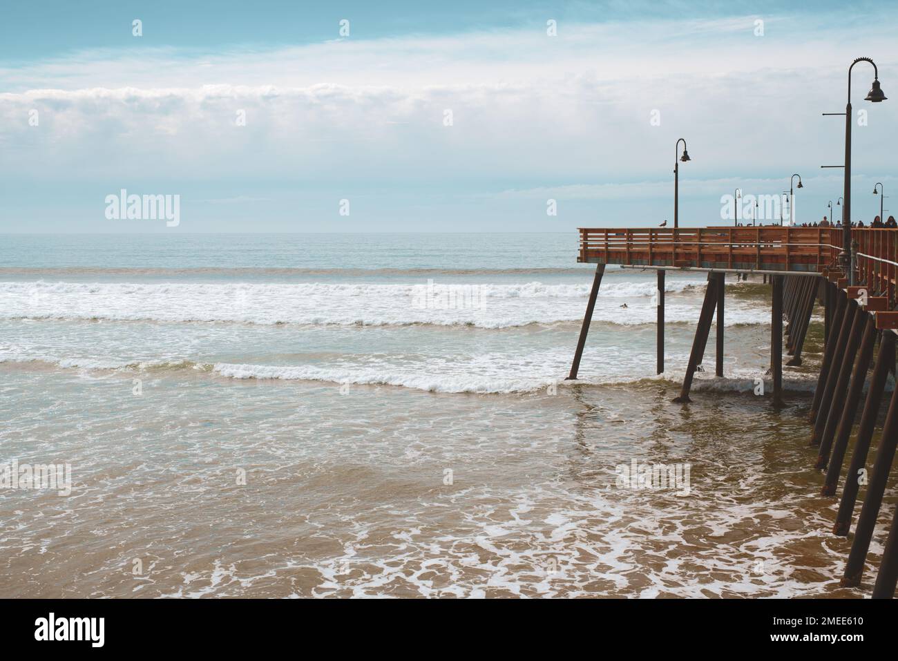 Holzpier am Strand, stürmischer Pazifik und wunderschöner bewölkter Himmel an der kalifornischen Zentralküste Stockfoto
