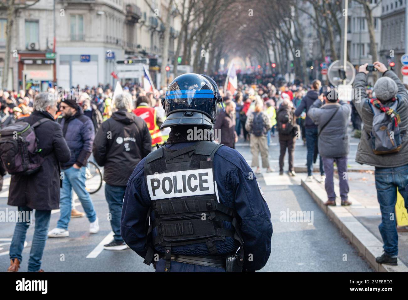 Frankreich, Lyon, 2023-01-19. Demonstration gegen die Rentenreform. Ein Polizist mit einem Helm auf dem Rücken, der die Demonstranten während des marschs beobachtet. Stockfoto