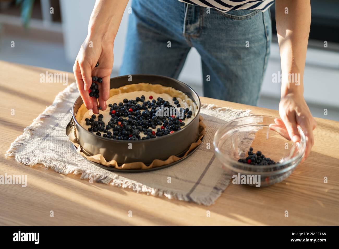 Nahaufnahmen einer Hausfrau, die Kuchen zubereitete und frische Blaubeeren für den festlichen Tisch hinzufügte Stockfoto