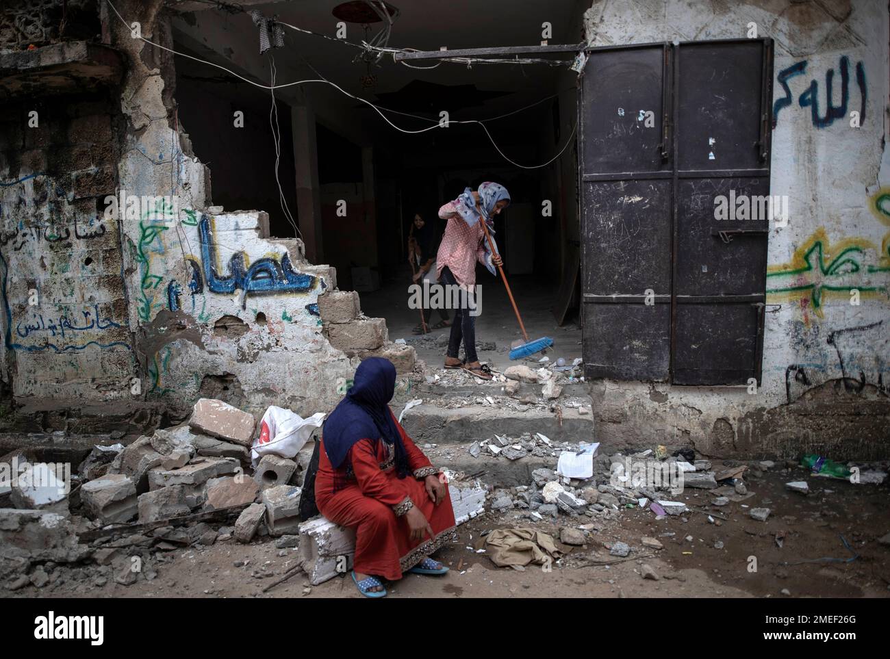 A Palestinian family remove the rubble from their damaged home ...