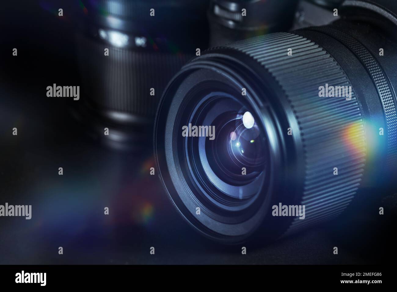 Digitale Fotografie, Objektiv einer schwarzen Kamera mit Reflexionen und Leuchtfackeln vor dunklem Hintergrund, technische Ausrüstung für Geschäft und Kunst, Kopierspac Stockfoto