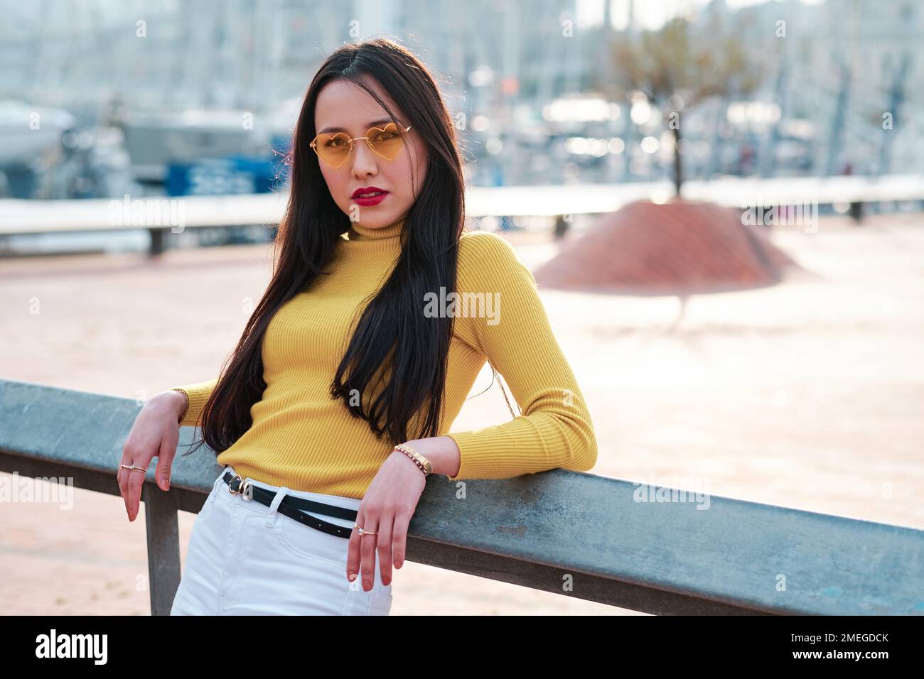 Eine Frau mit Sonnenbrille, die in die Kamera schaut, während sie draußen posiert. Stockfoto