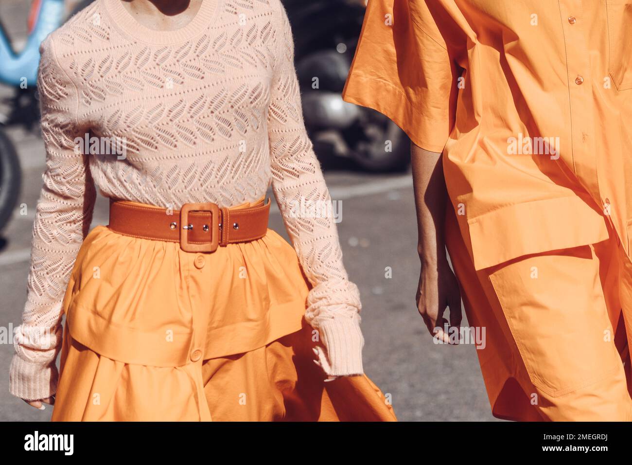 Mailand, Italien - 25. Februar 2022: Männchen und Weibchen in orangefarbenen Outfits, die an sonnigen Tagen während der Mailänder Modewoche laufen Stockfoto