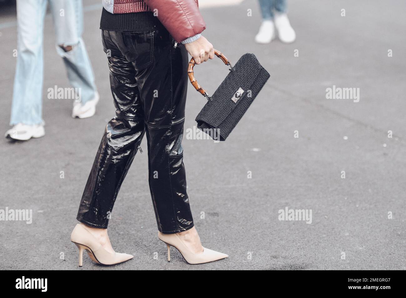 Mailand, Italien - 24. Februar 2022: Frau trägt warme Jacke, schwarze Lacklederhose und beige hohe Absätze Stockfoto