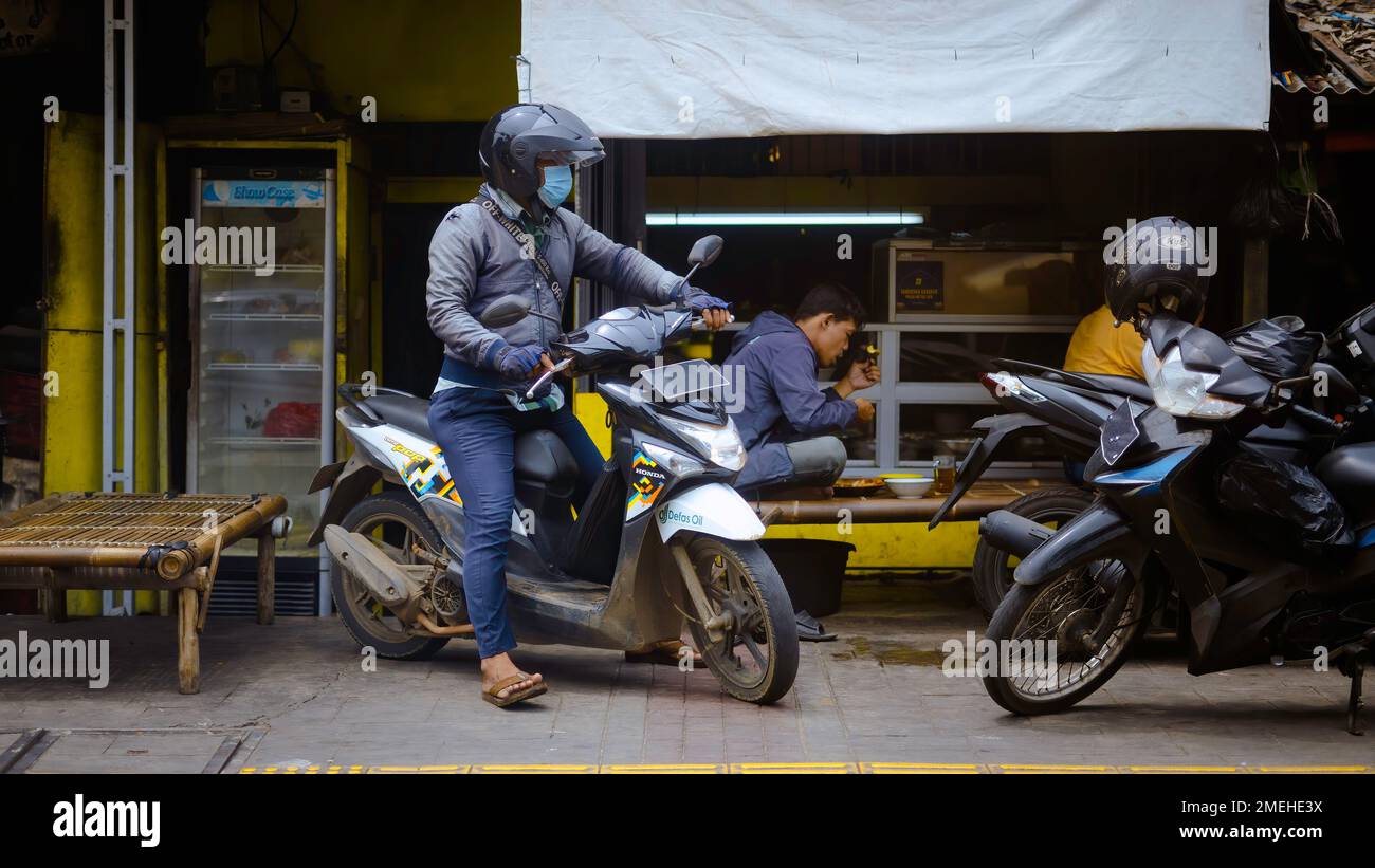 Einheimischer Mann, der während der Pandemie Jakarta Indonesia auf dem Markt von Jakarta mit Surgical Mask fährt Stockfoto