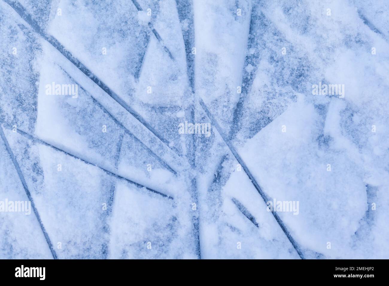 Leere Eisbahn mit Schlittschuhspuren nach der Sitzung im Freien. Eislaufbahn Textur mit Schnee bei Tageslicht bedeckt. Nahaufnahme von blauem Eislaufboden, CO Stockfoto