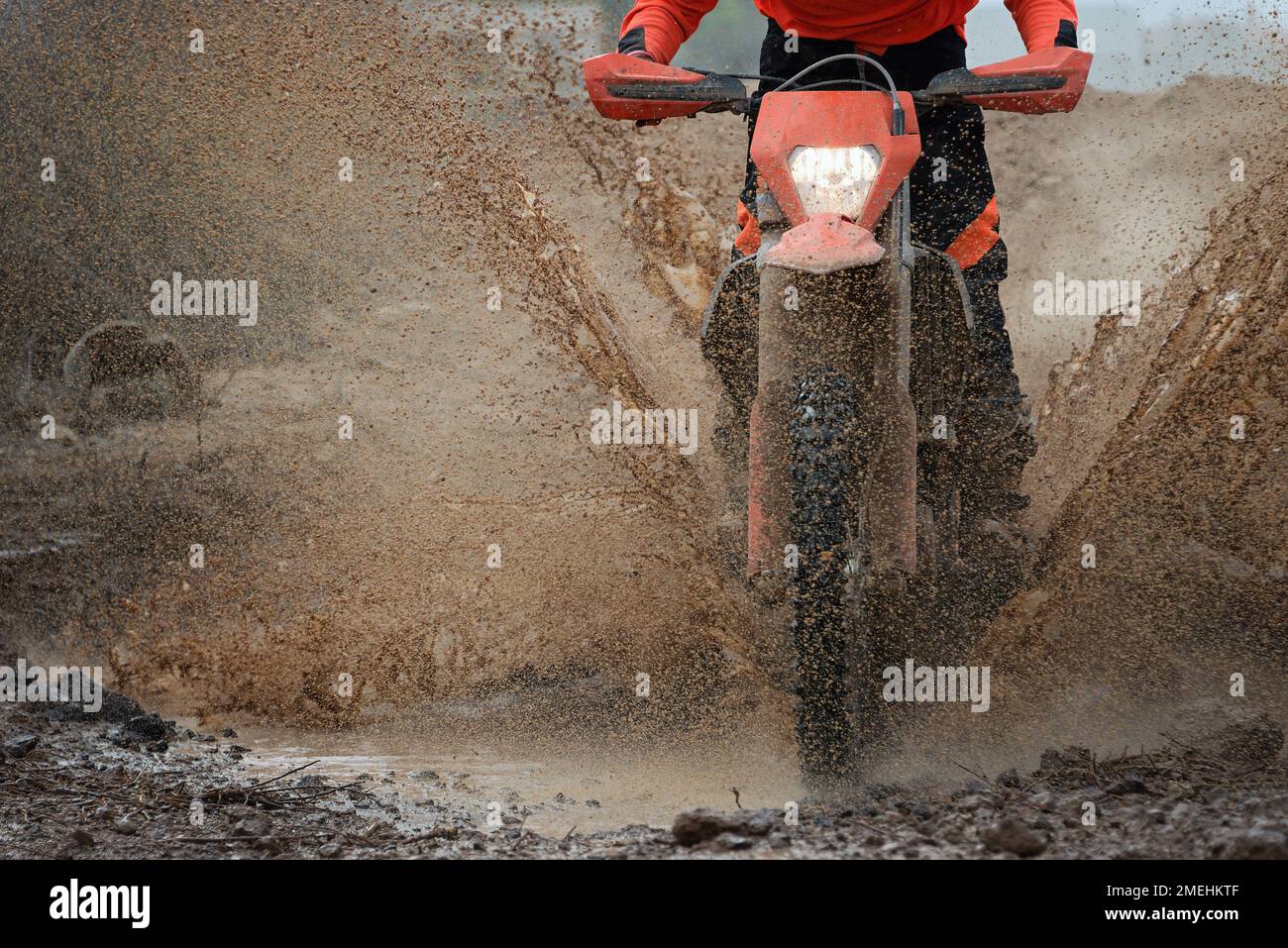 Motocross-Rennfahrer in nassem und schlammigem Gelände. Wasser und Schlamm spritzen überall hin und bedecken den Fahrer Stockfoto