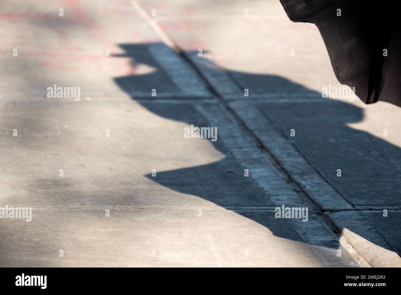 Schatten eines chassidischen Mannes mit Peyus. Wir überqueren die Lee Avenue in Williamsburg, Brooklyn, New York. Er ist wahrscheinlich ein Mitglied der Satmar-Gruppe. Stockfoto