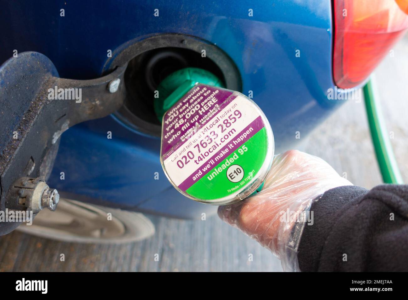 Das Auto mit bleifreiem tesco 95 E10 Benzin an der Zapfsäule füllen, Mann mit Kunststoffhandschuh, kent, großbritannien Stockfoto