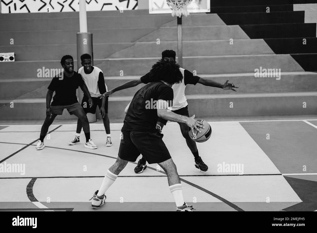 Afrikanische Freunde, die Basketball im Freien spielen – Fokus auf die richtigen Hände – Schwarz-Weiß-Bearbeitung Stockfoto