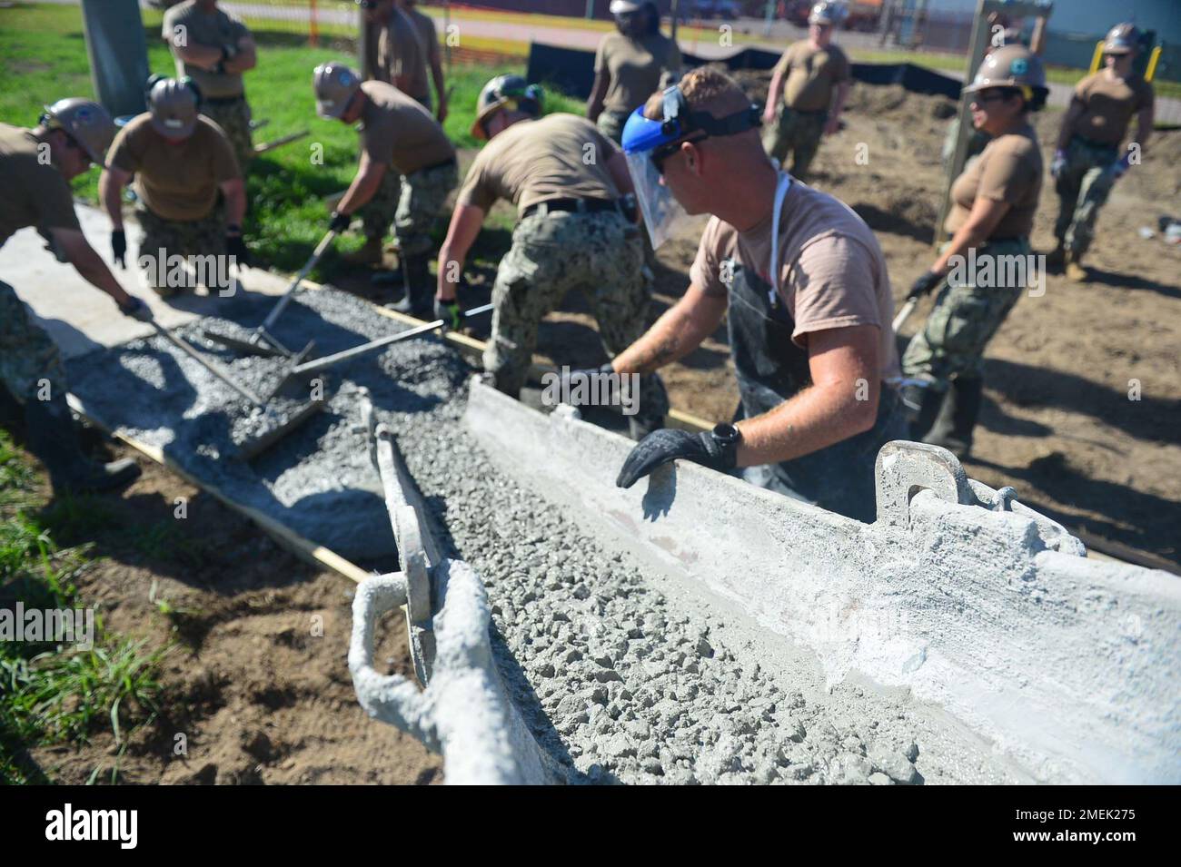 JOINT EXPEDITIONARY BASE LITTLE CREEK FORT STORY, VIRGINIA BEACH, VA (17. AUGUST 2022) USA Matrosen der Marine, die der Baubataillon-Wartungseinheit (CBMU) 202 zugeteilt sind, haben glatten und Ebenen frisch gegossenen Beton, ein Prozess, der auch als Eilbohlen bezeichnet wird, während des Projekts zum Austausch des Gehwegs an Bord der Joint Expeditionary Base Little Creek Fort Story. Stockfoto