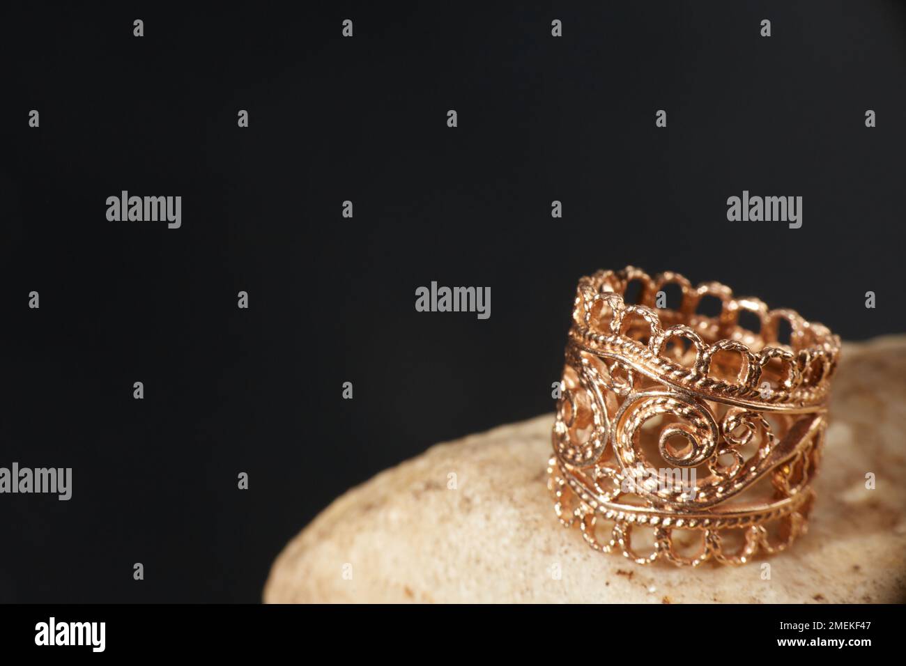 Ein goldener Ring auf einem Stein. Schwarzer Hintergrund mit Kopierbereich. Stockfoto