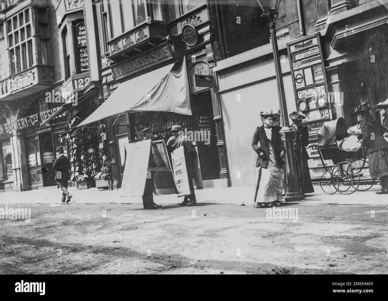 Scarborough, North Yorkshire, Großbritannien. Eine edwardianische Straßenszene mit zwei Männern, die Sandwichbretter für lokale Geschäfte mit sich führen. Ein Amateurfoto, aufgenommen um 1900. Stockfoto