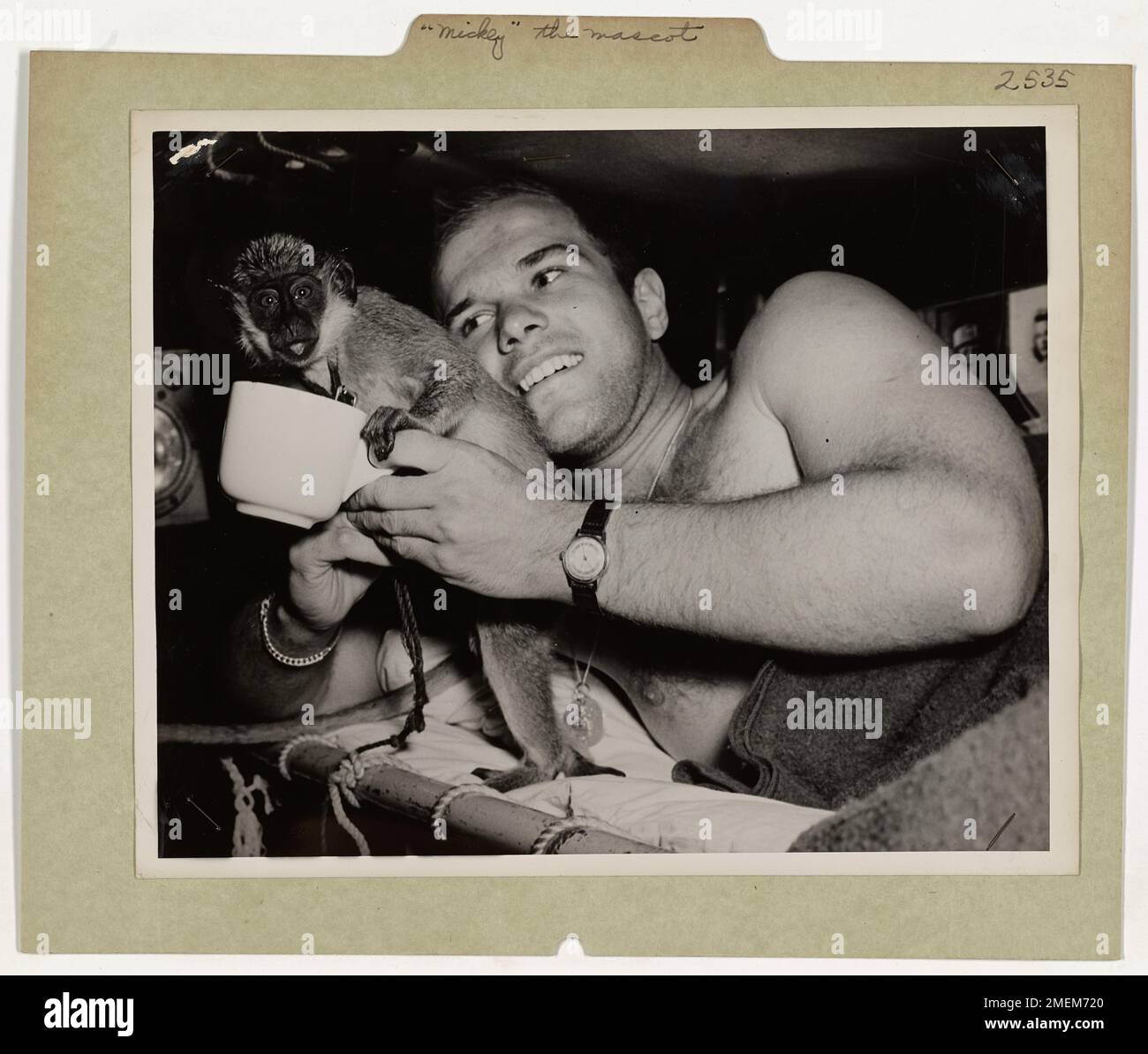 Offizielles Foto Der Küstenwache. „Mickey“, das Maskottchen von Coast Guard LCI, bekommt vor der Pensionierung einen Drink vom Seemann John Tumas, 80 Harbor View St., Boston, Massachusetts. Dieser Spinnenaffe wurde in Afrika von den erfahrenen Küstenwachmännern der Invasion erlangt, die dieses Landungsschiff bemannten. Stockfoto