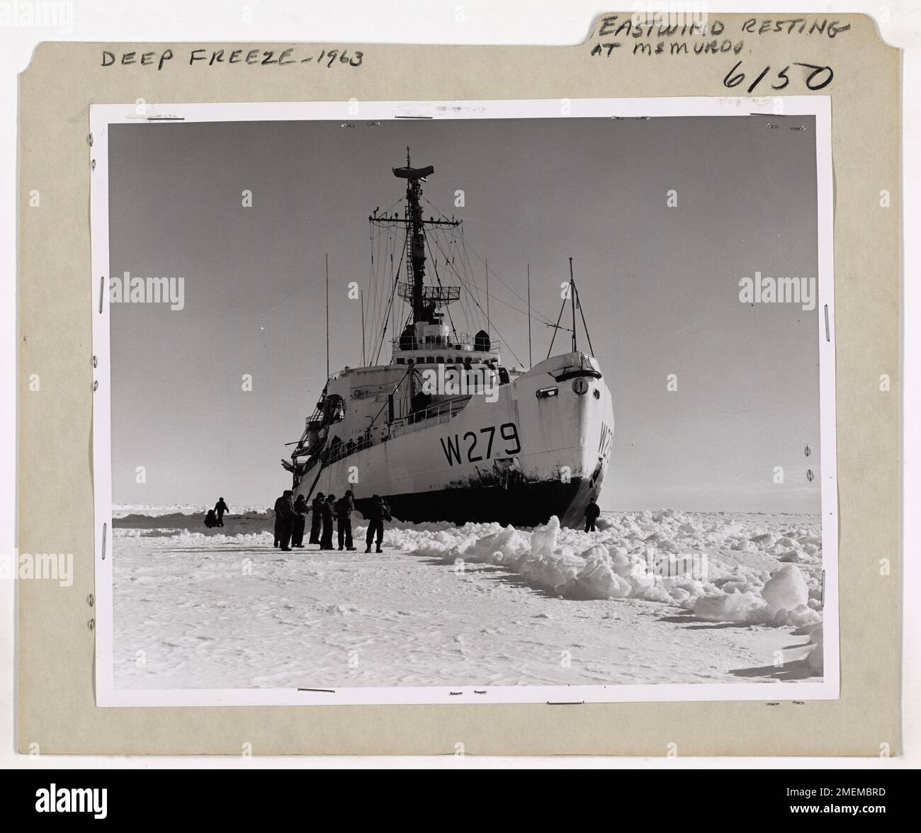 Eastwind ruht sich in McMurdo, Deep Freeze 1963 aus. Zwanzig Meilen von McMurdo Base entfernt, liegt der Eisbrecher Eastwind (WAGB-279) der US-Küstenwache auf einer Eishütte, nachdem er die mühsame Aufgabe hatte, durch den eingefrorenen Kanal von Frachtschiffen der Navy Task Force, die Männer, Vorräte und Ausrüstung zur Basis liefern, Blei aufzureißen. Crewmen genießen die Pause, trainieren auf dem Eis und ermuntern sich mit Kamera-Schnappschüssen. Das Eis in dieser Saison war das schwerste, das es je bei Deep Freeze Operations gab. Neben dem Transport von Treibstoff und Vorräten zu den McMurdo-Stützpunkten während dieser Operation half der Eastwind dabei, eine 60 km lange Kanalstrecke zu durchbrechen Stockfoto