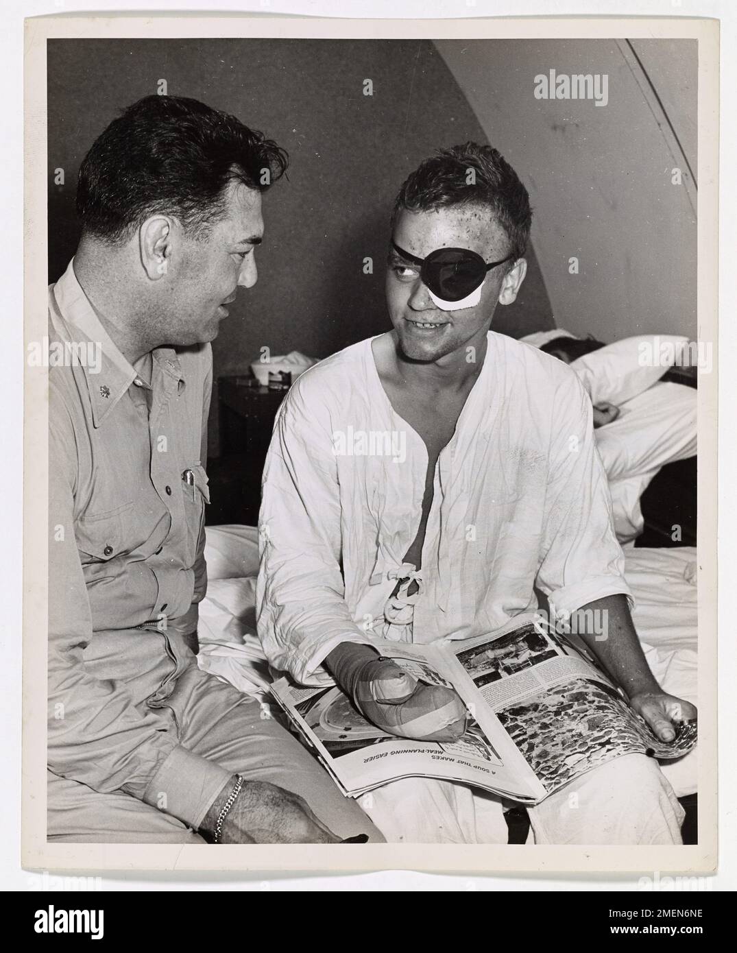 Der Kommandant der Küstenwache Jack Dempsey, ehemaliger Schwergewichtsmeister, besucht verwundete Veteranen in einem Krankenhaus in Guam und steigert damit die Moral der Küstenwache, Marines und Soldaten. Er spricht mit Richard R. Baab, einem Iwo Jima-Veteranen. Stockfoto