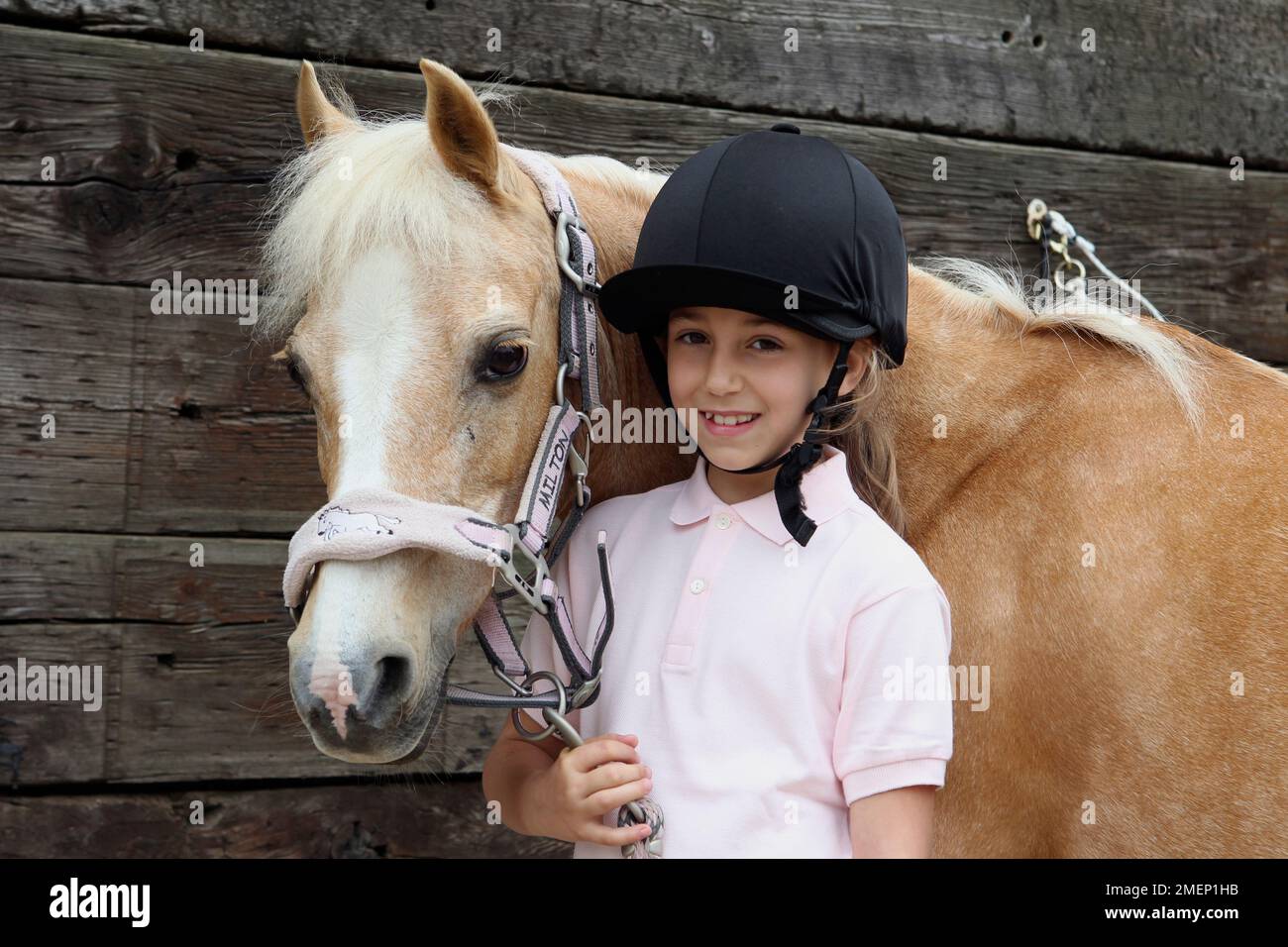 Ein Mädchen, das mit palomino-Pferd posiert, in die Kamera schaut, lächelt Stockfoto