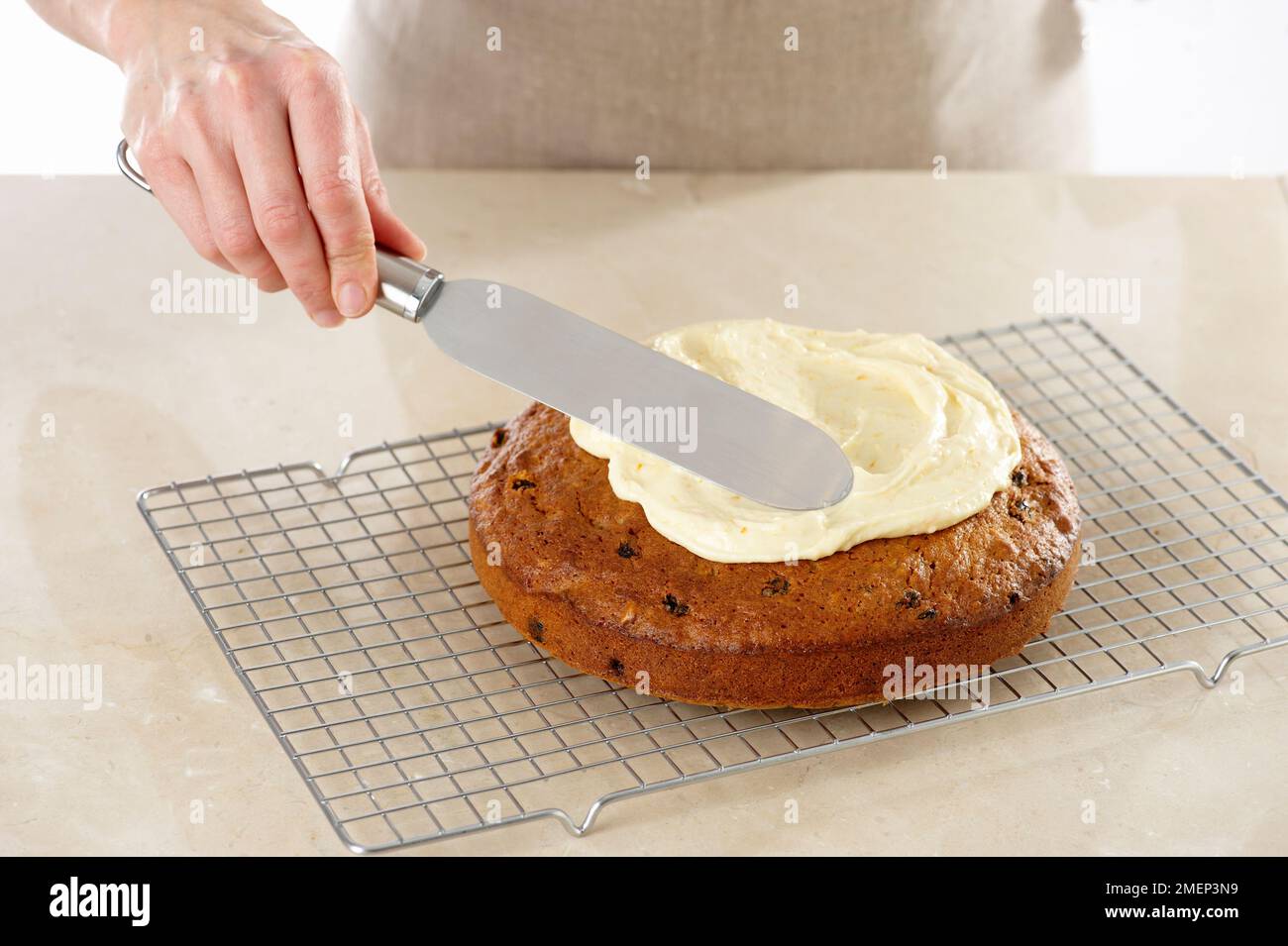 Karottenkuchen, mit dem Palettenmesser das Sahnehäubchen auf den Kuchen streuen Stockfoto