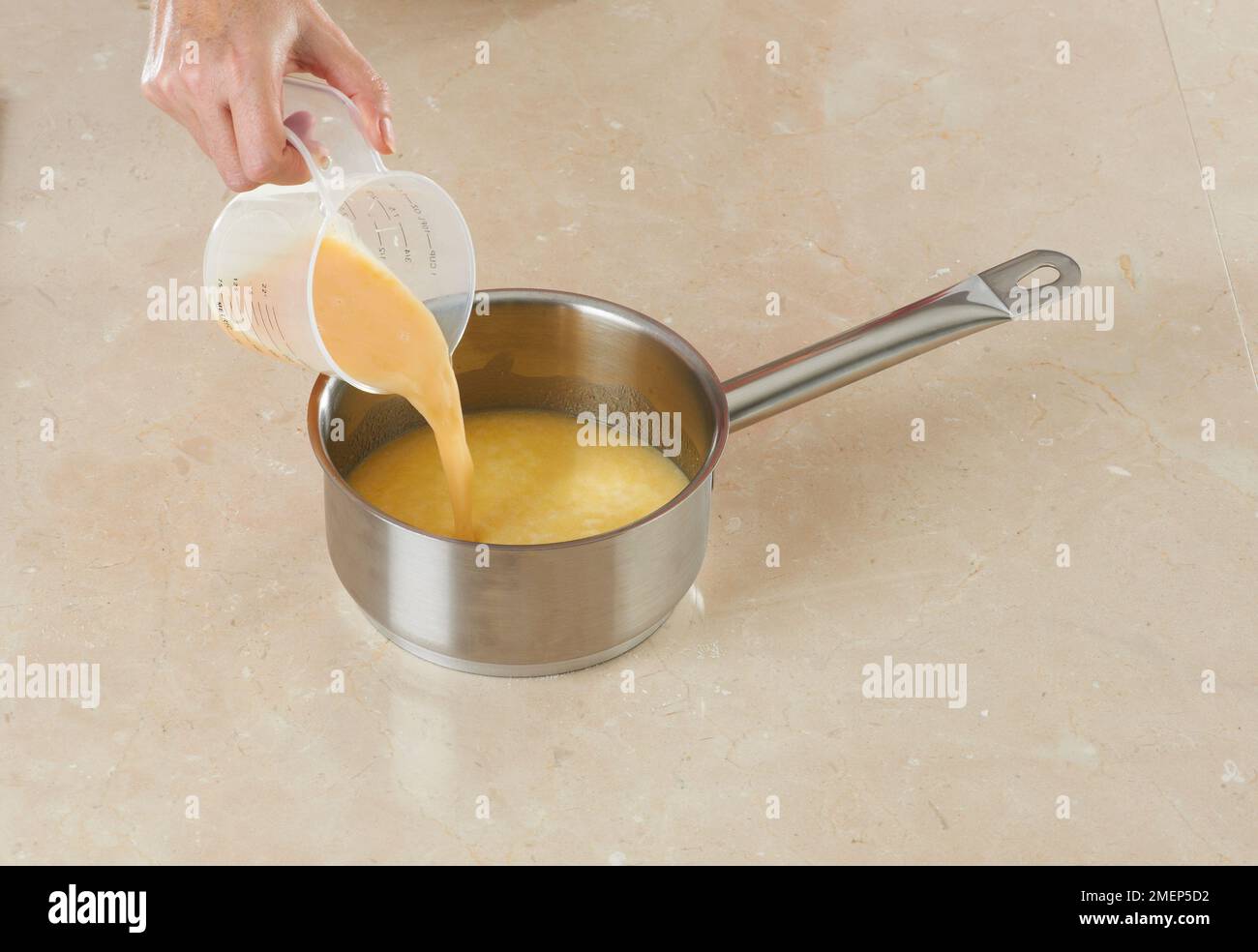 Doughnuts machen, Eier in Milch-Butter-Mischung gießen Stockfoto