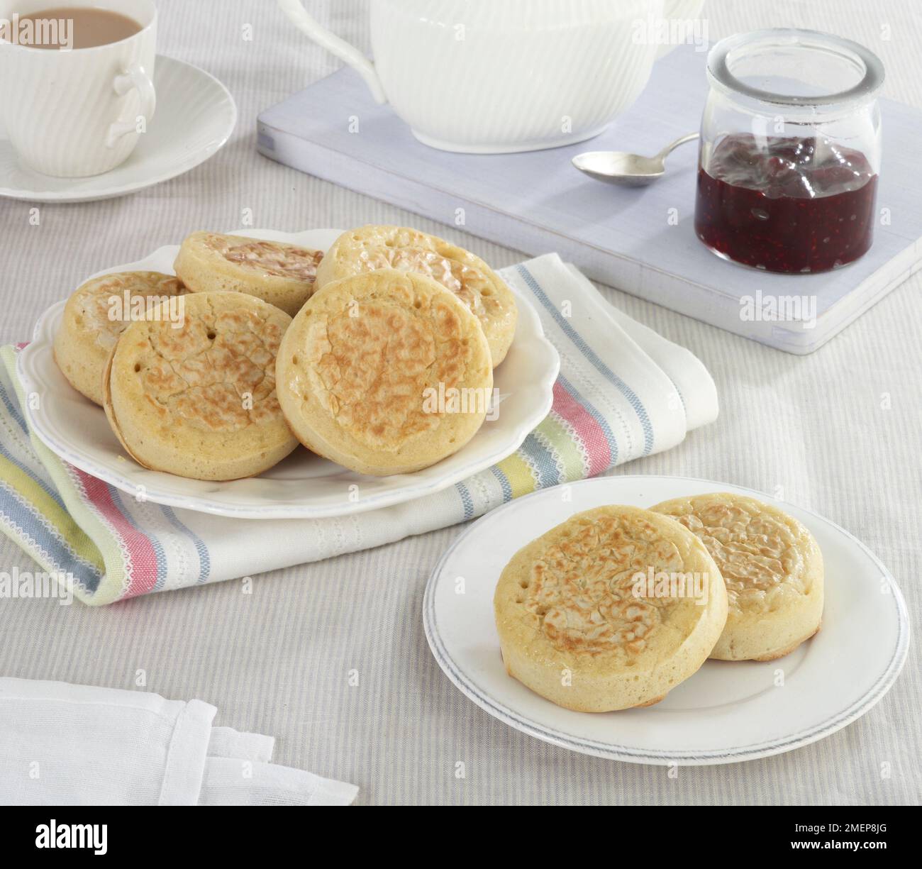 Crumpets werden mit Marmelade und einer Tasse Tee serviert Stockfoto