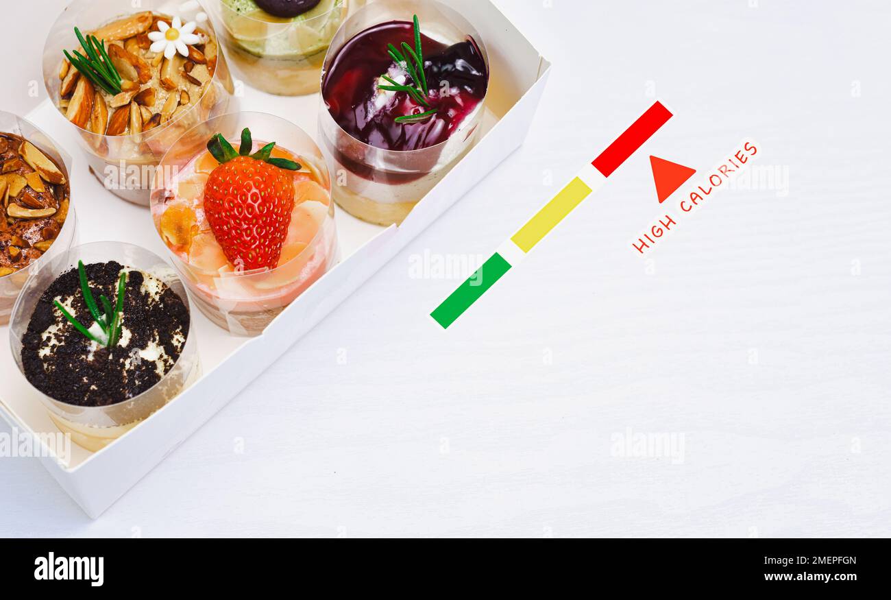 Kalorienreiches Dessert mit Käsekuchen auf weißem Holztisch, das Konzept der gesundheitsschädlichen Lebensmittel Stockfoto