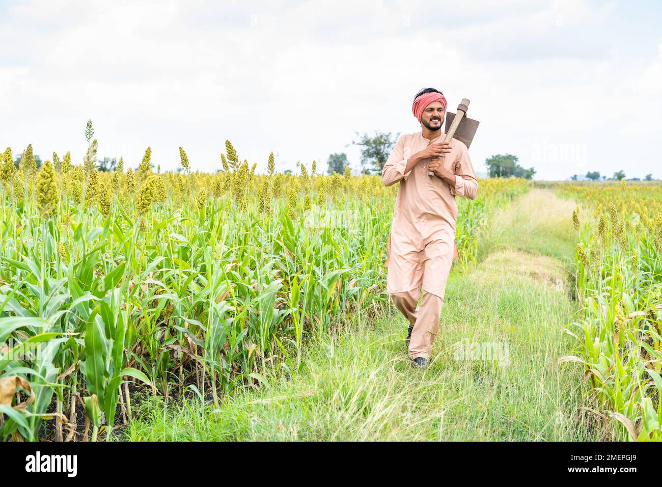 Ein vollständiges Bild des Bauern mit Pik, der sich auf einem Spaziergang auf der landwirtschaftlichen Maisfarm umsieht - Konzept für täglichen Arbeiter, Erntesaison und ländliches indien Stockfoto