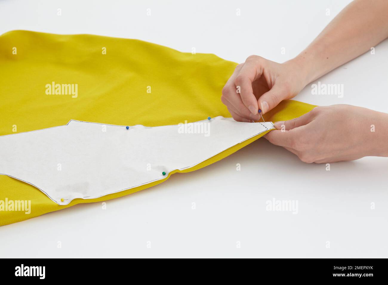 Das Kleidungsstück wird an gelbem Stoff befestigt, Nahaufnahme Stockfoto