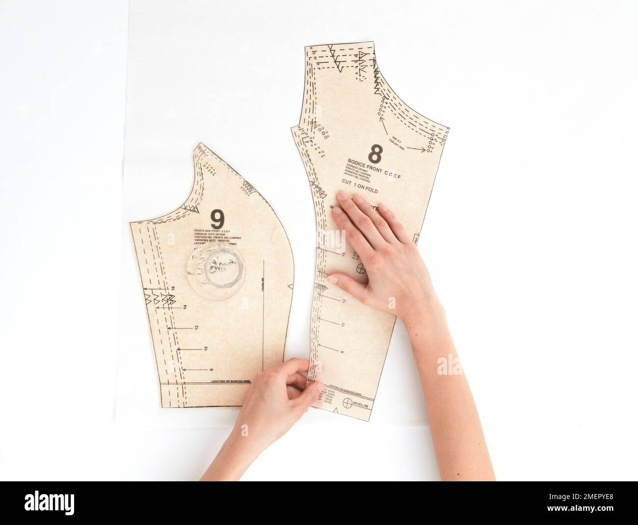 Frau, die das Dressmaking-Muster auf Papier positioniert, Blick von oben Stockfoto