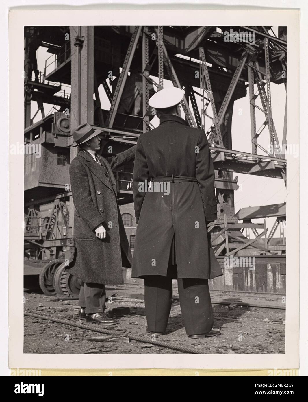 Sgt. O'Donnell von der Reading Company Police erklärt den Ladevorgang an einen Freiwilligen Port Security Force Officer aus Philadelphia, mit großen Ladestrukturen im Hintergrund. Diese Abbildung zeigt die Rolle der lokalen Sicherheitskräfte bei der Unterstützung des Hafenbetriebs während des Krieges. Stockfoto