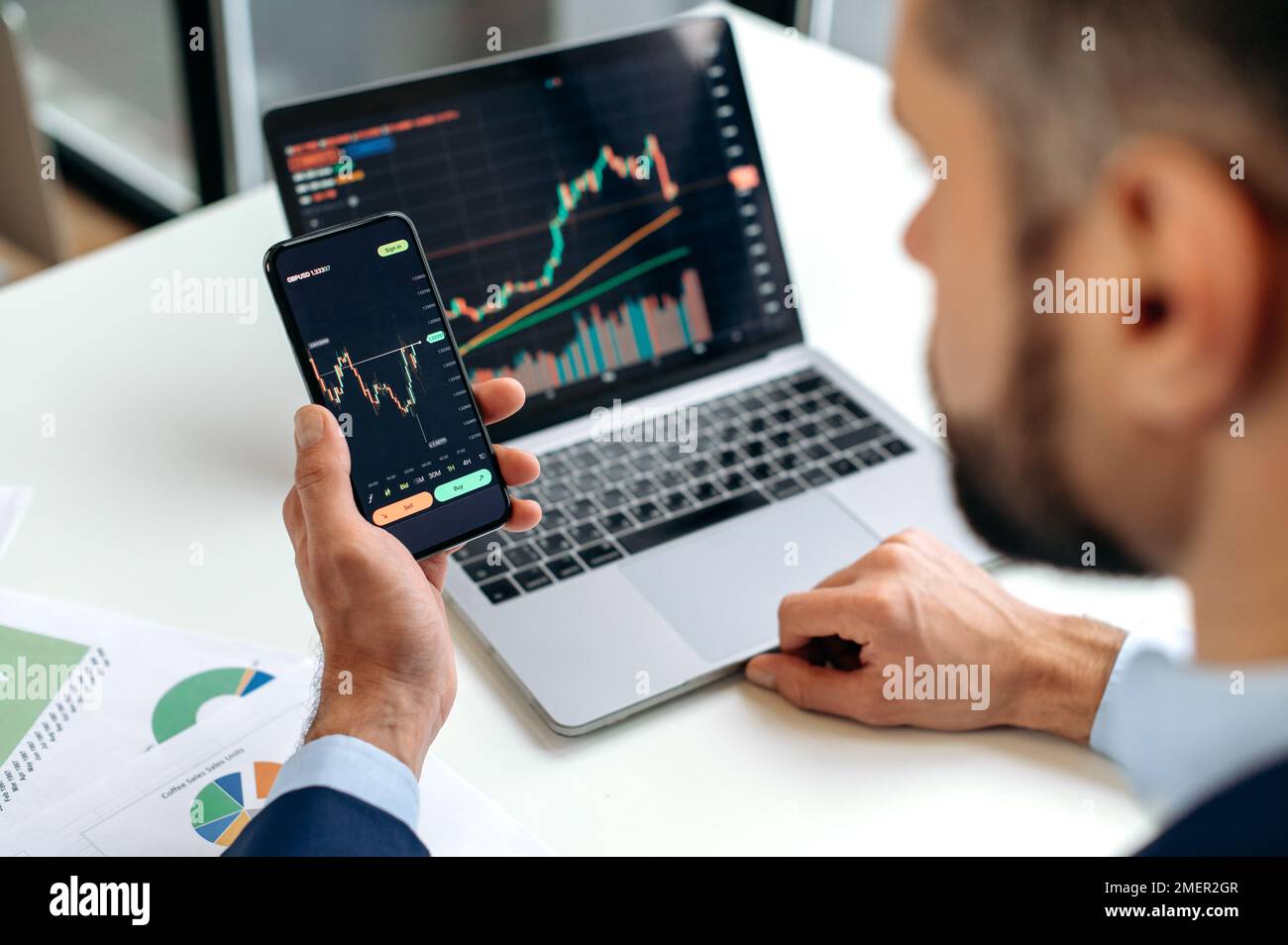 Analysten von Händlern, die eine Mobilfunk-App für Kryptowährungsaktienmärkte verwenden, analysieren Diagramme zu Handelsdaten, Index für das Investitionswachstum, planen die Strategie. Nahaufnahme von männlichen Händen, die ein Smartphone halten Stockfoto