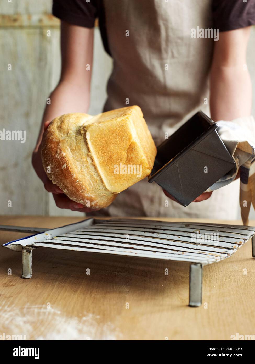 Entfernen des gebackenen Brotlaibs aus der Brotdose Stockfoto