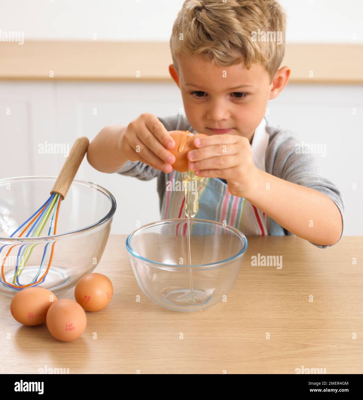 Junge knacken Ei in Schüssel, 4 Jahre Stockfoto